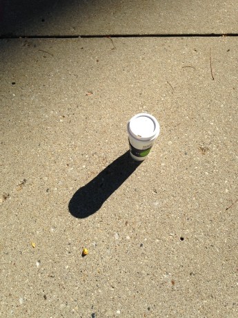 Starbucks cup on sidewalk casting shadow