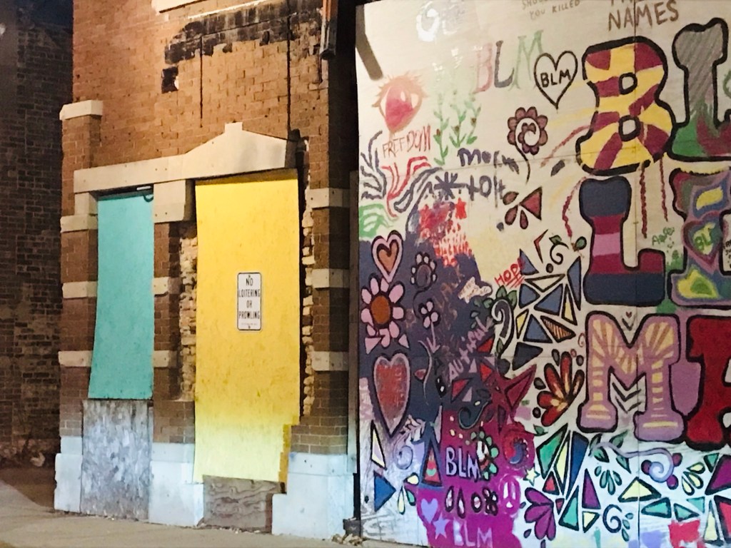 Brightly colored boards and a mural adorn a decrepit brick building