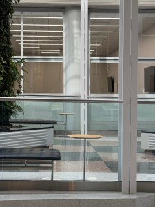 Office building lobby in silver and light green colors, with spare, minimalist furniture, lots of silver metal and glass, and many vertical and horizontal lines