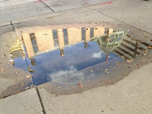 Grohmann Museum reflected in a puddle on a sunny day