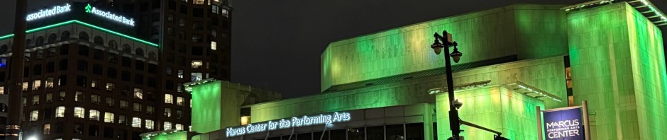 Associated Bank River Center and Marcus Center for the Performing Arts buildings in downtown Milwaukee, illuminated with green lights