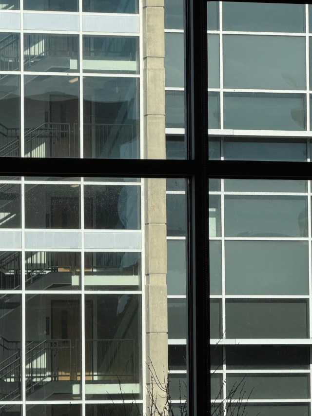 An abstract view of highrise building windows, as viewed from the window of another building, with emphasis on many dark and light perpendicular lines