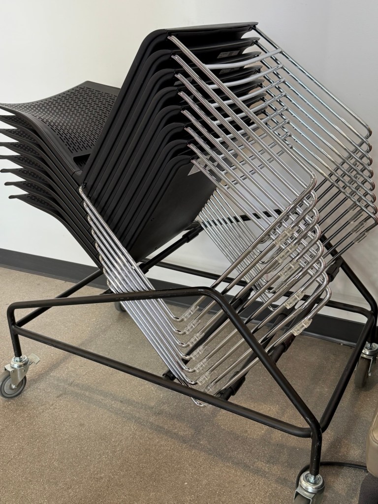 Unusual, attractively-designed stackable event chairs, stored atop a wheeled platform rack