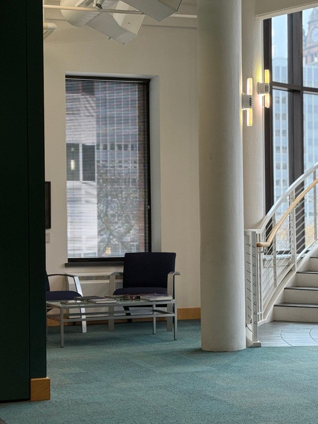 Chairs beside a window, near a spiral staircase in the atrium area of the Grohmann Museum in Milwaukee